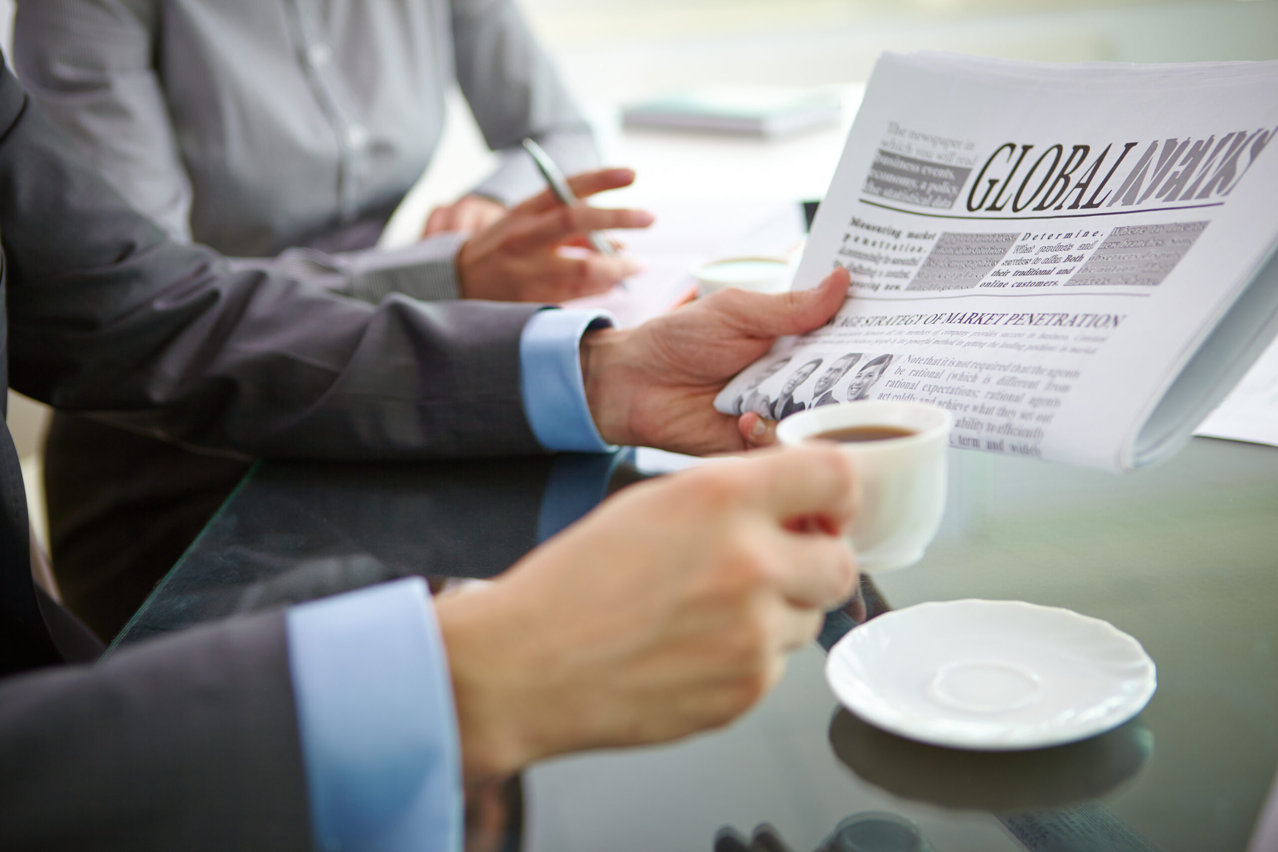 Businessman with newspaper having coffee at workplace